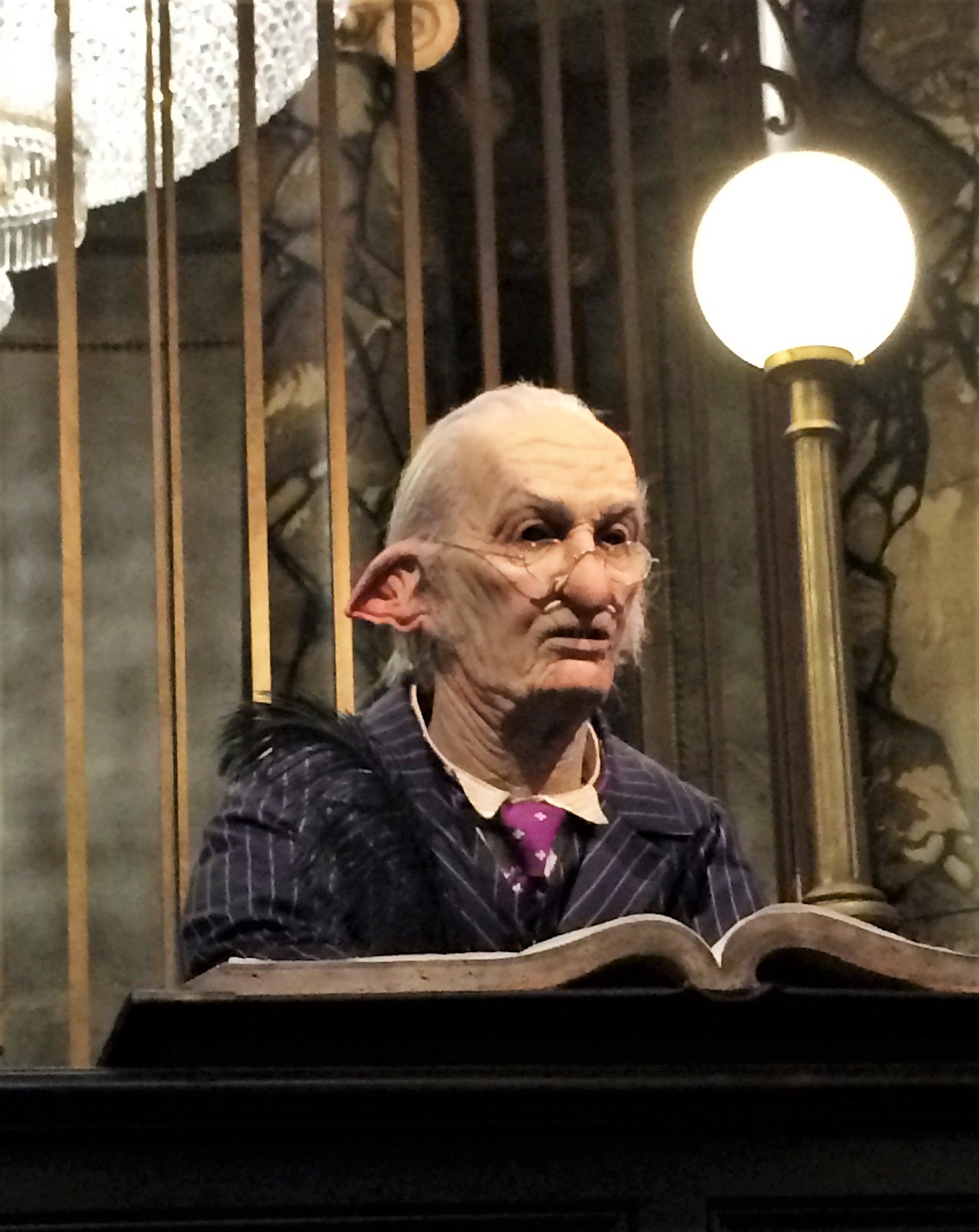 Goblin in Gringotts Bank attending to his account ledger.