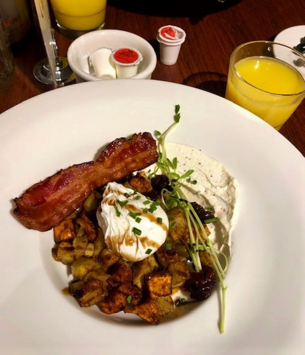 Breakfast at Black Star Farms, with a poached egg over sweet potato hash, a side of bacon,  and fresh orange juice.